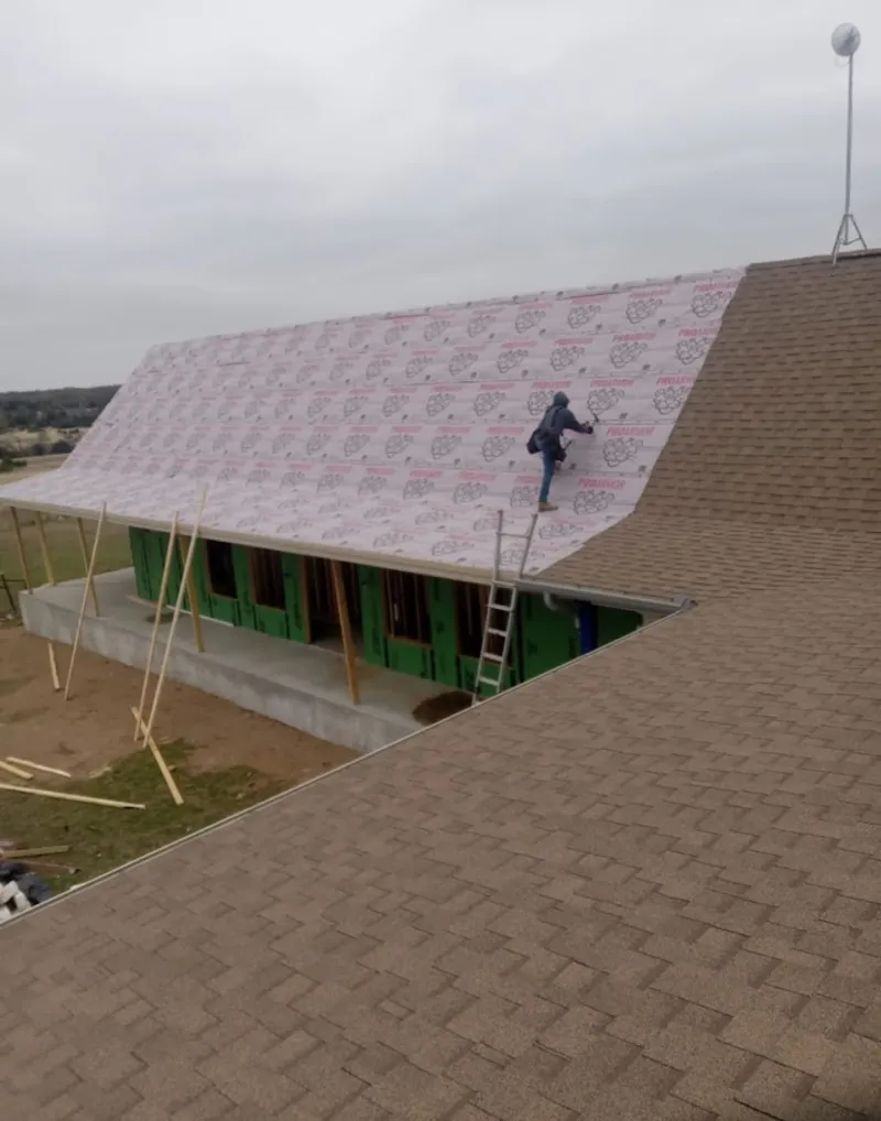 Worker preparing underlayment for a metal roof installation in Emmett